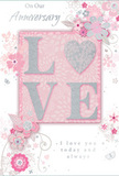 The anniversary card shown in this image has the quiet romance of a pastel bouquet, the sort you might send across Erith to celebrate years of shared memories. At its heart, the design features the word LOVE, boldly spelled out in raised letters coated with a dusting of fine, shimmering glitter. The glitter is soft and refined, glinting in silvery and pearly tones that lend the letters a frosted, tactile quality, as if lightly kissed by morning frost. These letters rest on a panel of blush pink that glows gently, standing out against the paler, almost pearly border of the card. Surrounding this central word is an arrangement of illustrated flowers and leaves, composed with the grace of a florist building a hand-tied bouquet. The blossoms are drawn in a palette of blush pinks, pale mauves, and pearlescent whites, with outlines in soft grey and occasional touches of metallic silver that catch the light. Petals curve inwards and outwards with subtle shading, giving a sense of depth and softness, while slender vines and curling tendrils weave through the floral cluster, suggesting gentle movement. The background is a consistent wash of delicate pink, deepening slightly near the centre and softening toward the corners, creating a dreamy, halo-like effect. Fine decorative flourishes-scrolls, tiny petals, and perhaps hints of butterfly shapes-are scattered discreetly, enhancing the sense of celebration without overwhelming the design. Elegant script lettering, printed in a muted grey, carries heartfelt anniversary messages such as On Our Anniversary and I love you today and always, their curves echoing the floral swirls. Altogether, the card feels like a tender, handcrafted tribute to lasting love, as thoughtfully composed as a bespoke anniversary arrangement delivered by Erith Flowers to local homes and riverside apartments.